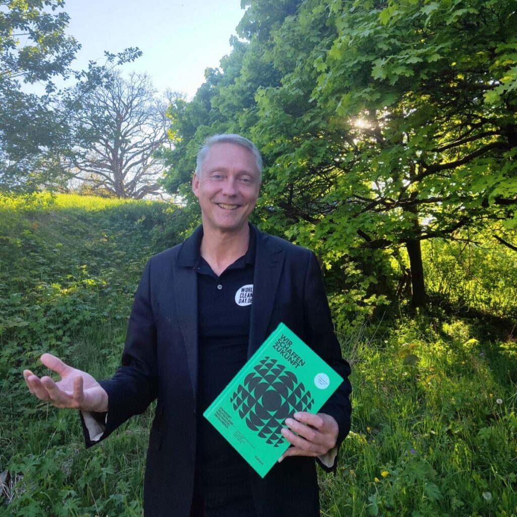 Holger Holland mit dem Buch „Wir schaffen Zukunft“ in der Natur